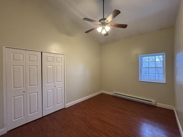 unfurnished bedroom featuring baseboard heating, a closet, vaulted ceiling, ceiling fan, and dark hardwood / wood-style flooring