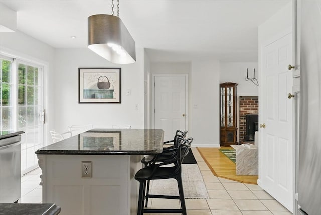 507 Towne St, North Attleboro, MA 02760 - kitchen featuring dishwasher, light tile patterned flooring, a breakfast bar area, a center island, and dark stone countertops