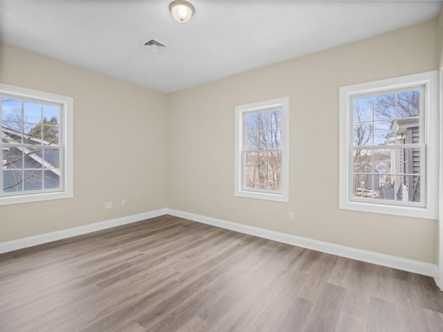 spare room featuring baseboards, a wealth of natural light, and wood finished floors