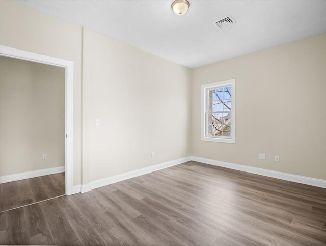 spare room featuring baseboards, visible vents, and wood finished floors