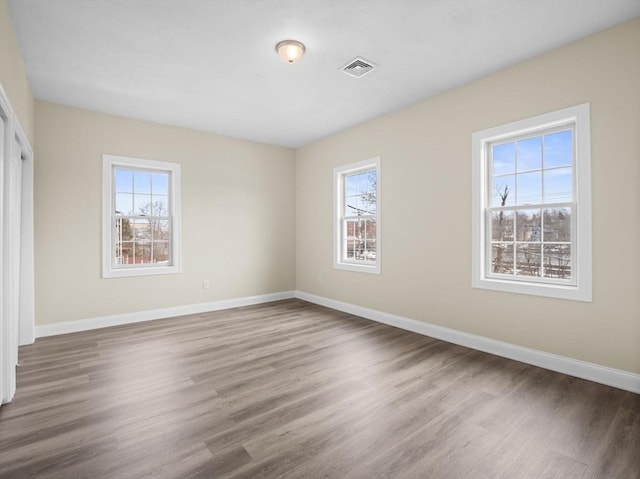 unfurnished bedroom featuring wood finished floors, visible vents, and baseboards