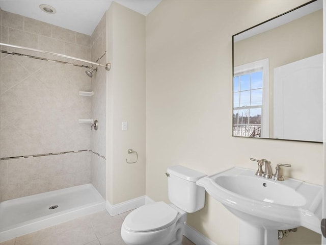 bathroom with tile patterned flooring, toilet, a sink, baseboards, and a shower stall