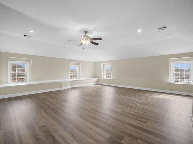 empty room featuring dark wood-style floors, baseboards, visible vents, and a tray ceiling