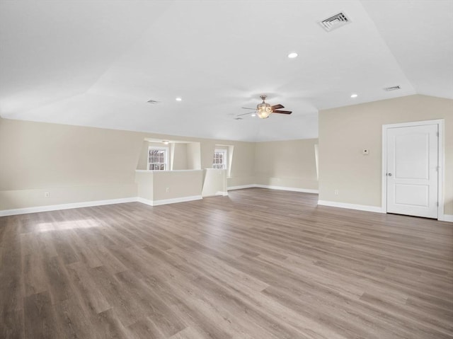 unfurnished living room featuring visible vents, vaulted ceiling, baseboards, and wood finished floors