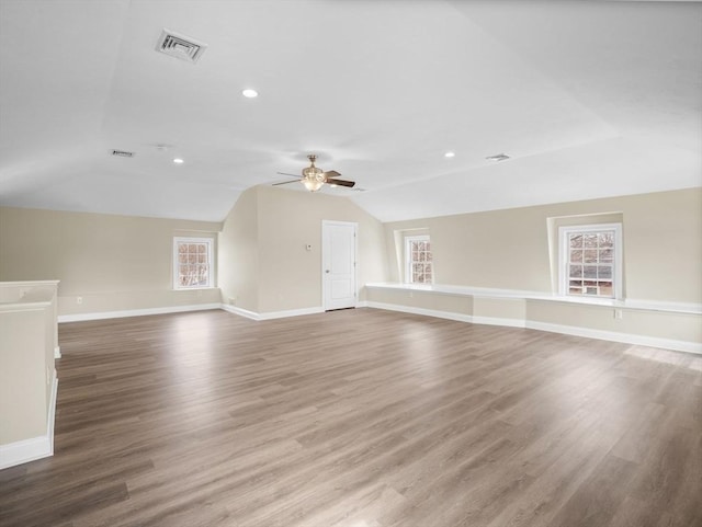 bonus room featuring baseboards, visible vents, vaulted ceiling, and wood finished floors