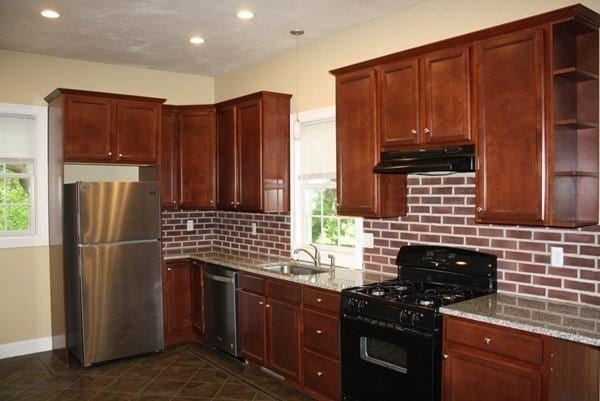 kitchen featuring open shelves, appliances with stainless steel finishes, a sink, light stone countertops, and under cabinet range hood