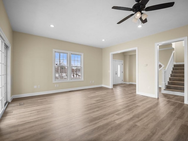 unfurnished living room featuring stairs, recessed lighting, wood finished floors, and baseboards