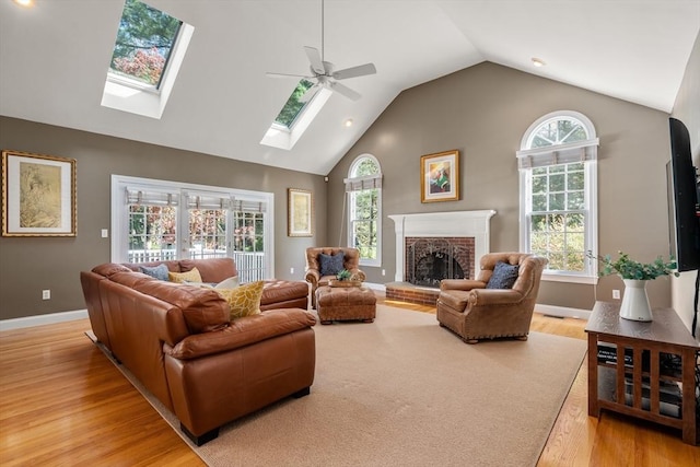 20 Peakham Rd, Sudbury, MA 01776 - living room featuring ceiling fan, a skylight, a fireplace, high vaulted ceiling, and light wood-style floors