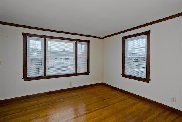 unfurnished room featuring ornamental molding, a wealth of natural light, baseboards, and dark wood-style floors