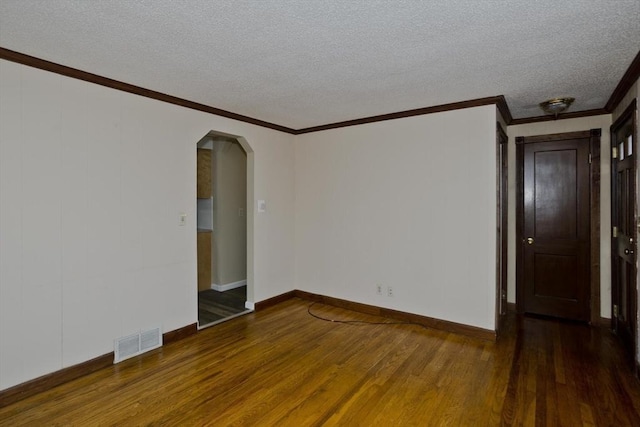 empty room with visible vents, arched walkways, a textured ceiling, crown molding, and wood finished floors