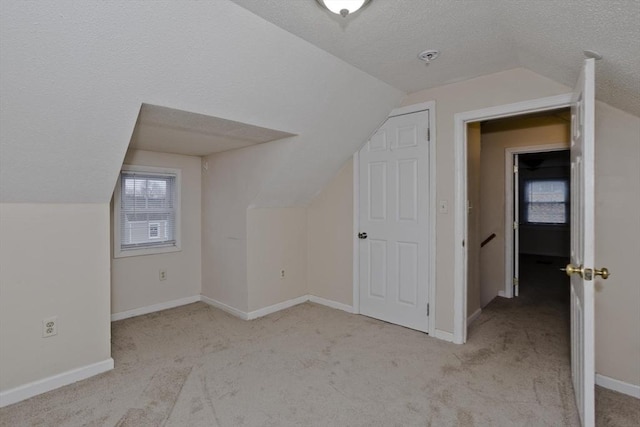 additional living space with baseboards, carpet flooring, a textured ceiling, and vaulted ceiling