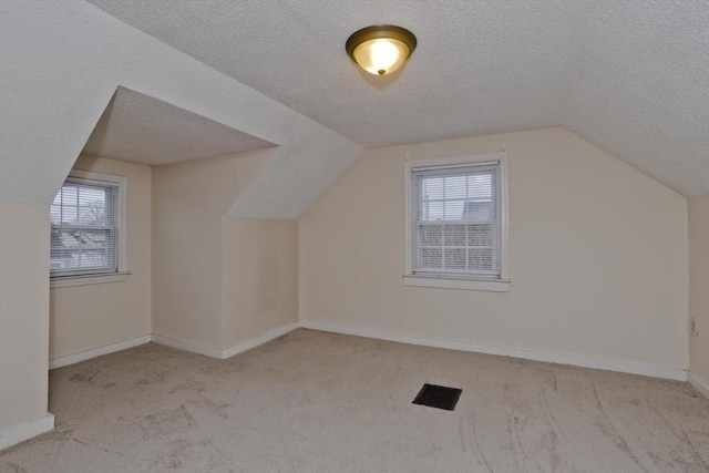bonus room with carpet floors, baseboards, vaulted ceiling, and a textured ceiling