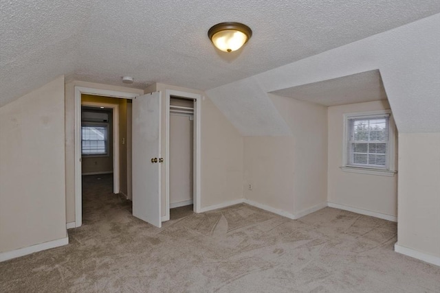 bonus room with lofted ceiling, a textured ceiling, baseboards, and carpet floors