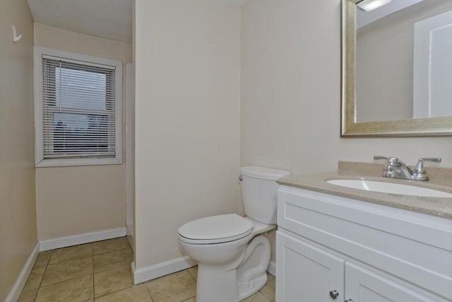bathroom featuring toilet, tile patterned floors, vanity, and baseboards