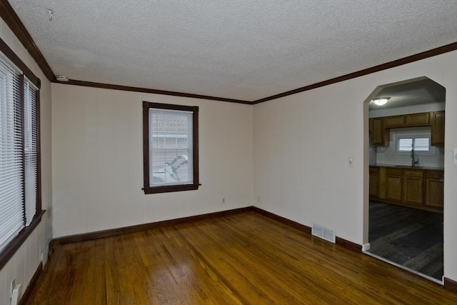 spare room with dark wood-type flooring, a textured ceiling, arched walkways, visible vents, and a sink