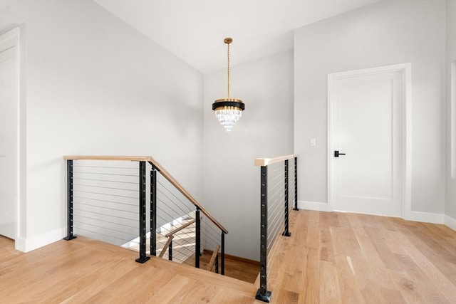 stairs with wood-type flooring and a chandelier