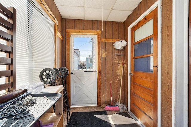 doorway to outside with a paneled ceiling and wood walls