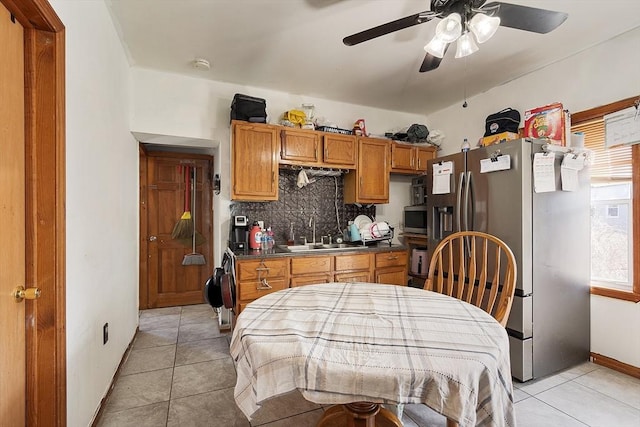 kitchen featuring tasteful backsplash, a sink, appliances with stainless steel finishes, a ceiling fan, and brown cabinetry