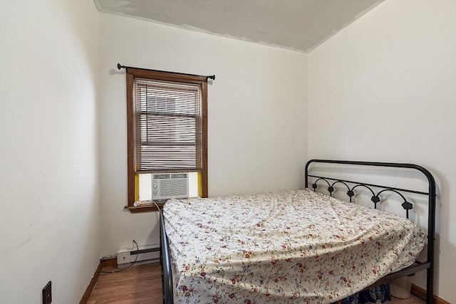 bedroom featuring wood finished floors, cooling unit, a baseboard heating unit, and baseboards