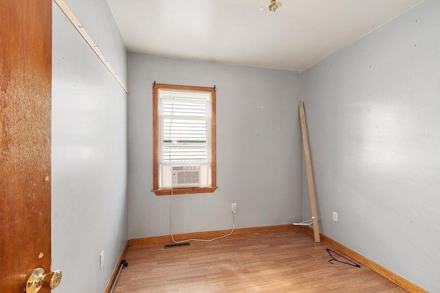 spare room featuring light wood finished floors, visible vents, and baseboards