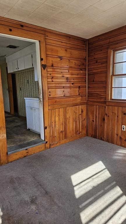empty room with wood walls and carpet floors