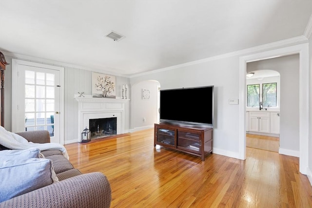 273 Greendale Ave, Needham, MA 02494 - living area featuring arched walkways, ornamental molding, light wood-style floors, a fireplace with flush hearth, and baseboards