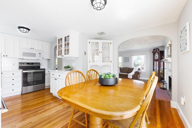 273 Greendale Ave, Needham, MA 02494 - dining space featuring arched walkways, light wood finished floors, baseboards, and a fireplace