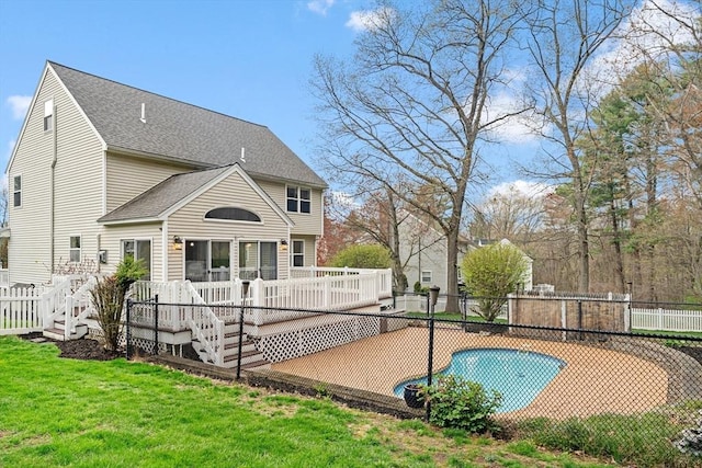 rear view of house featuring roof with shingles, fence, a lawn, and a deck