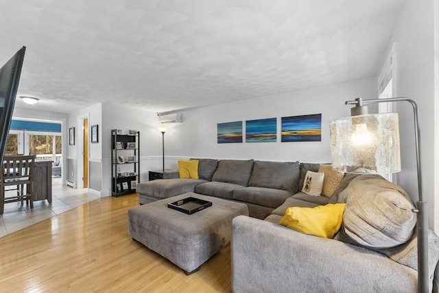 living room featuring an AC wall unit, light wood-style floors, and baseboards