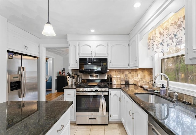 kitchen featuring a sink, appliances with stainless steel finishes, dark stone countertops, and white cabinetry