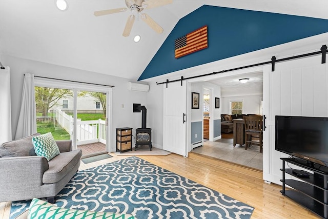 living room with a ceiling fan, high vaulted ceiling, a barn door, and light wood-type flooring