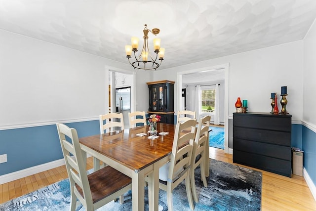dining room with baseboards, an inviting chandelier, and light wood-style flooring