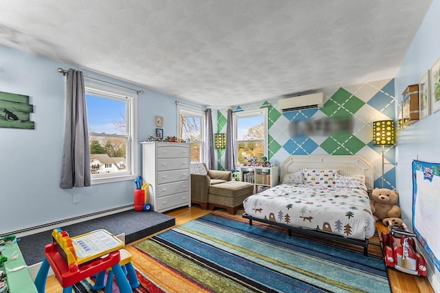 bedroom featuring a baseboard heating unit, a textured ceiling, a wall mounted AC, and wood finished floors