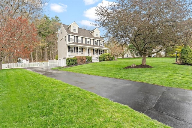 view of front facade featuring fence, covered porch, and a front yard