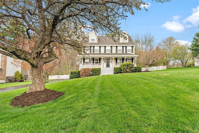 view of front of house featuring covered porch, fence, and a front yard
