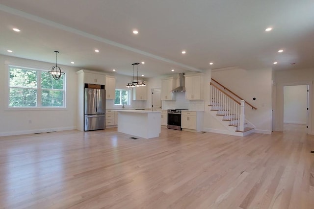 12 Willow St, Pepperell, MA 01463 - kitchen featuring appliances with stainless steel finishes, wall chimney exhaust hood, a center island, open floor plan, and white cabinetry