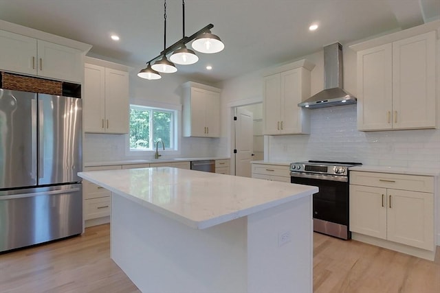 12 Willow St, Pepperell, MA 01463 - kitchen featuring appliances with stainless steel finishes, wall chimney exhaust hood, light wood-type flooring, a kitchen island, and white cabinetry