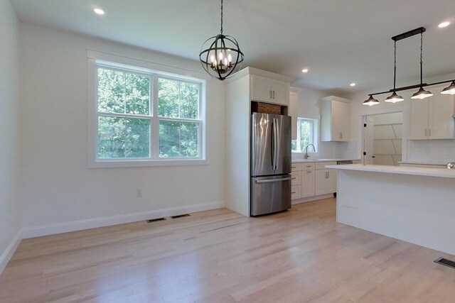 12 Willow St, Pepperell, MA 01463 - kitchen with freestanding refrigerator, light countertops, light wood-style flooring, a chandelier, and white cabinetry