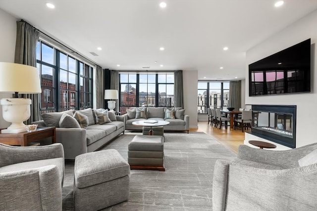 living room featuring light wood-style floors, a multi sided fireplace, visible vents, and recessed lighting