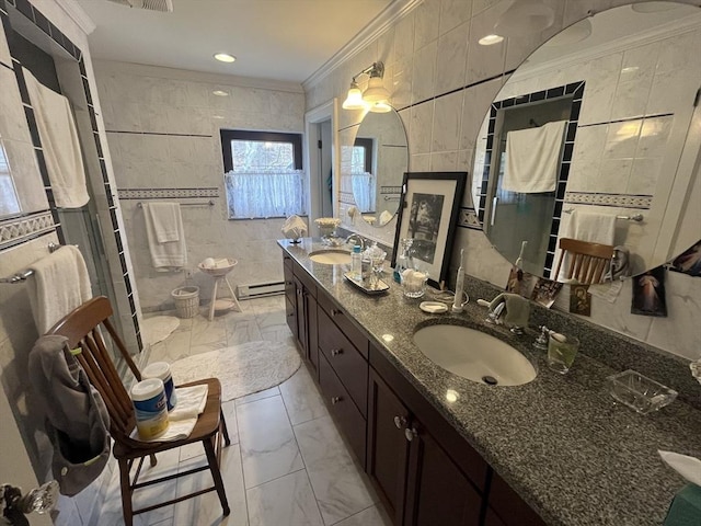 full bathroom featuring marble look tiles, baseboard heating, ornamental molding, double vanity, and tile walls
