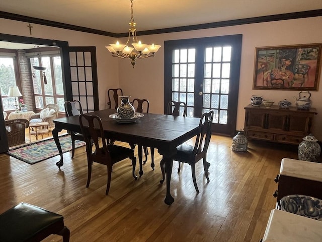 dining room featuring ornamental molding, french doors, hardwood / wood-style flooring, and a chandelier