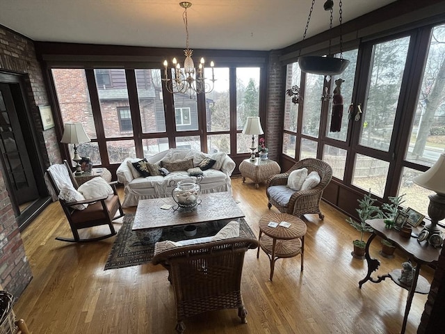 sunroom / solarium featuring wood finished floors and a chandelier