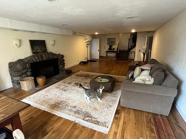 living room featuring wood finished floors, a fireplace, baseboards, and stairs