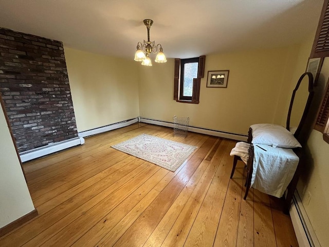 unfurnished dining area with a chandelier, hardwood / wood-style floors, a baseboard radiator, and baseboards