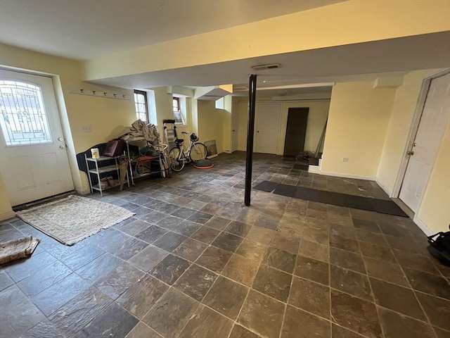 basement with stone tile floors, plenty of natural light, and baseboards