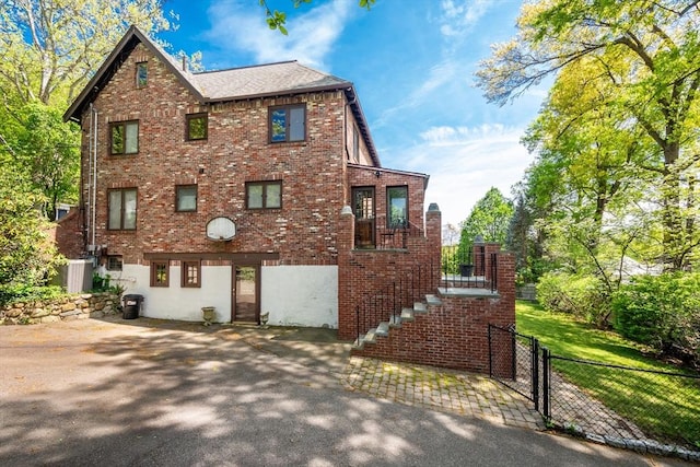 view of front of house featuring fence, brick siding, and stairway