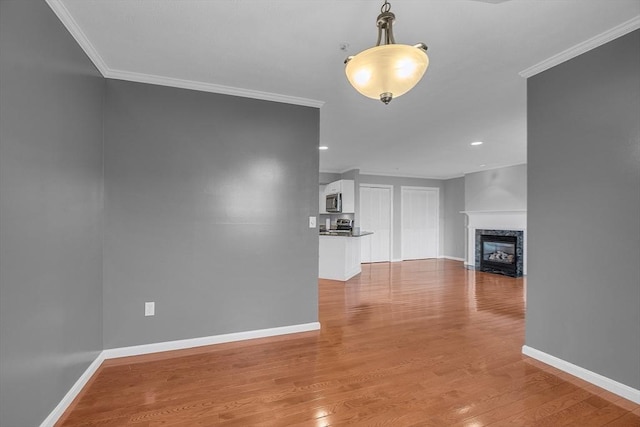 unfurnished living room featuring a fireplace, ornamental molding, and hardwood / wood-style flooring