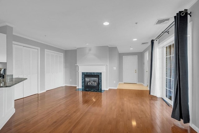 unfurnished living room featuring light hardwood / wood-style floors, crown molding, and a premium fireplace