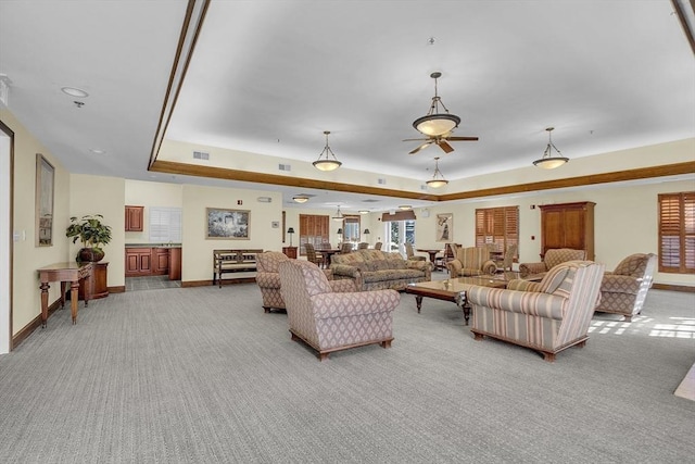 carpeted living room with a tray ceiling and ceiling fan