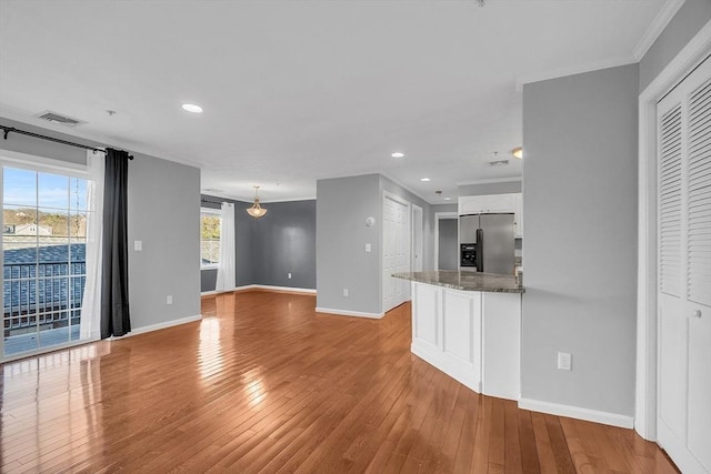 unfurnished living room with light hardwood / wood-style flooring and ornamental molding